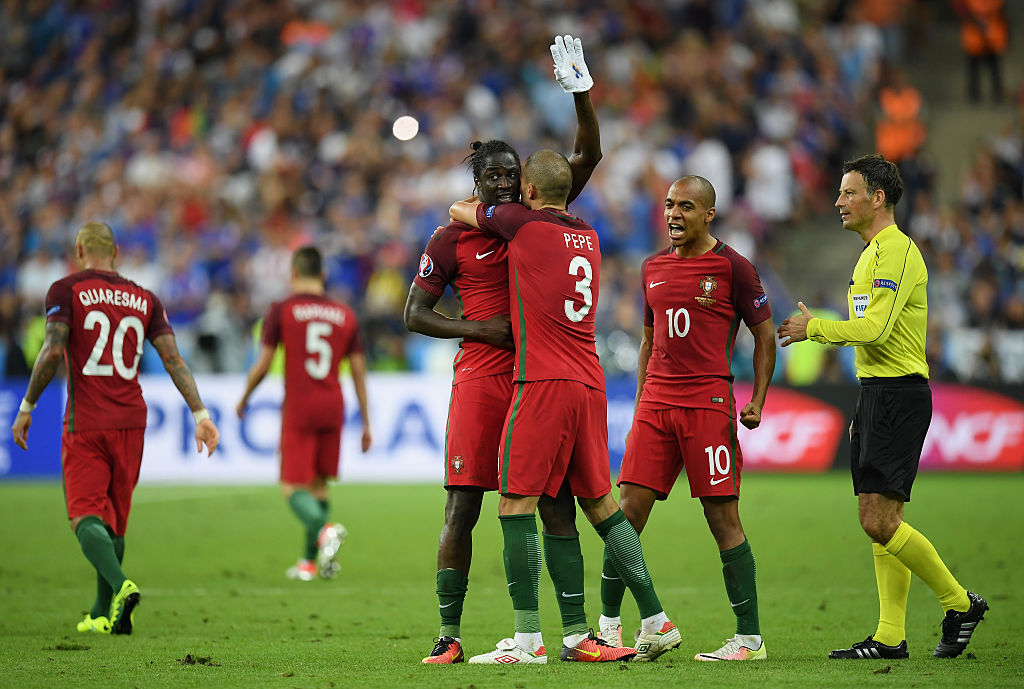 PARIS, FRANCE - JULY 10: Eder of Portugal celebrates after scoring the opening goal by putting on a white glove and is mobbed by teammates Pepe and Joao Mario as Referee Mark Clattenburg looks on during the UEFA EURO 2016 Final match between Portugal and France at Stade de France on July 10, 2016 in Paris, France. (Photo by Matthias Hangst/Getty Images)
